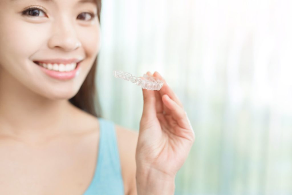 wentzville-invisalign-clear-aligner-tray Woman holding Invisalign clear aligner in Wentzville at Bankhead Orthodontic Specialists